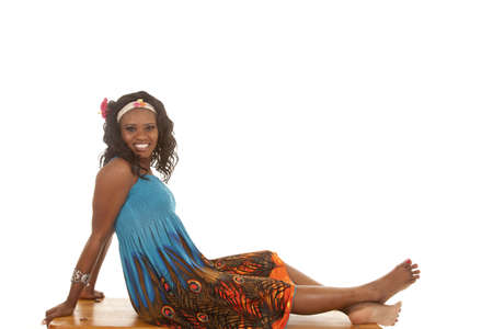 An African American relaxing on a bench in her colorful dress.の写真素材