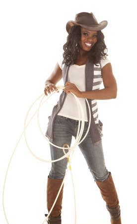 An African American in her cowgirl hat and holding on to a rope with a smile on her face.の写真素材