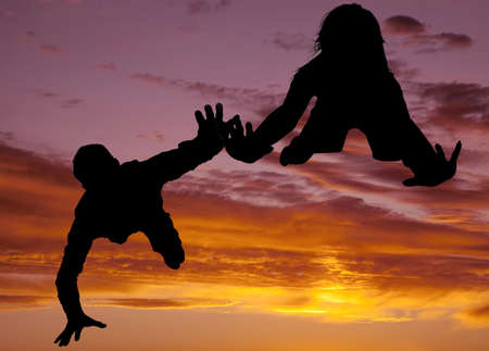 A silhouette of a man and a woman flying through the beautiful skyの写真素材
