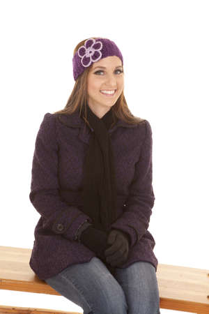 A woman sitting on a bench with a smile on her face with a warm hat on.の写真素材