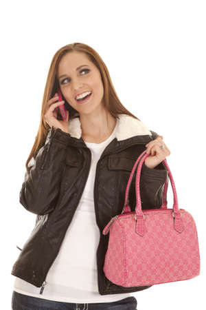 A woman talking on the phone holding on to her pink purse with a smile.の写真素材