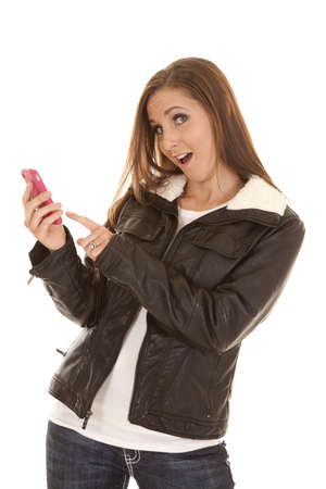 a woman with a fun expression on her face texting on her pink phoneの写真素材