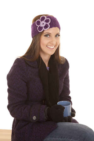 A woman with a smile on her face holding on to a mug sitting on a benchの写真素材