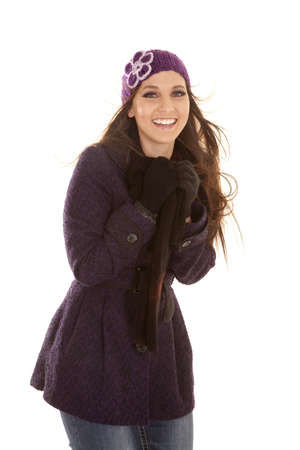 A woman in her winter coat and hat with the wind blowing with a smile on her lips.の写真素材