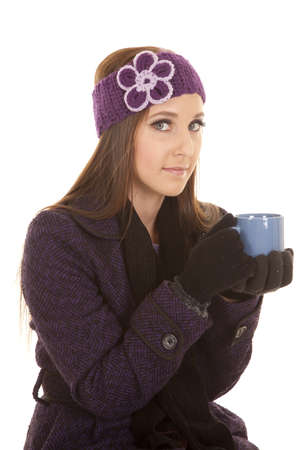 a woman holding on to her cup while wearing her winter coat and hat.の写真素材