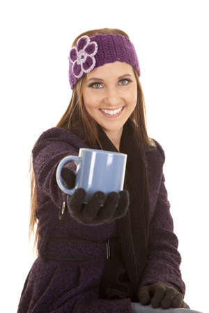 a woman smiling in her winter clothes holding out her cup.の写真素材