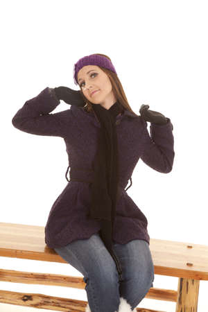 a woman sitting on a bench stretching while wearing her winter coat.の写真素材