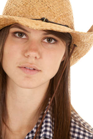 A close up of a woman's face while she is wearing a cowgirl hat with a serious expression.の写真素材