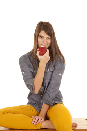 A woman sitting on a bench relaxing holding on to her apple that has a bite out of itの写真素材