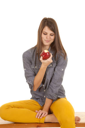 a woman looking down at her apple getting ready for another bite.の写真素材