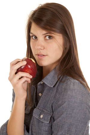 A close up of a woman eating an apple with a shocked expression on her face.の写真素材