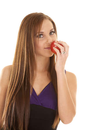 A woman with a small smile on her lips smelling an apple.の写真素材