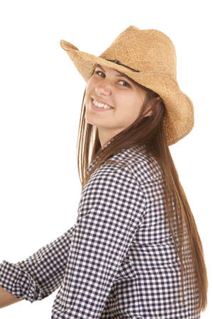 a woman sitting and looking over her shoulder with a big smile wearing her cowgirl hat.の写真素材