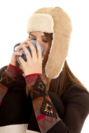 A woman drinking something from a mug in her warm clothing.の写真素材