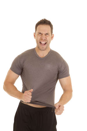 A man trying to rip off his tight fitting shirt.の写真素材