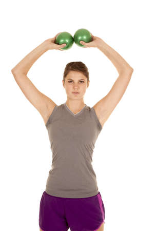A woman lifting her weighted green balls over her head.の写真素材