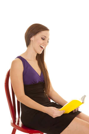 A woman with a big smile on her face looking at her book studying for school or workの写真素材