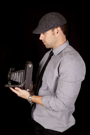 A man holding on to his antique camera with a serious expression on his face.の写真素材