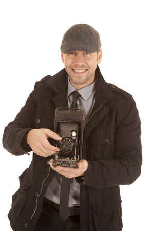 A man with a smile on his face holding on to a antique camera taking a picture.の写真素材