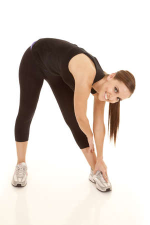 A woman with a smile on her face stretching out her legs and body.の写真素材