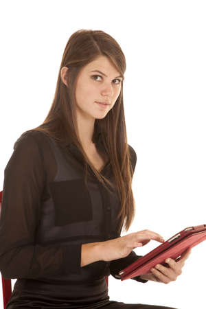A woman with a serious expression on her face working and studying on her electronic tablet.の写真素材