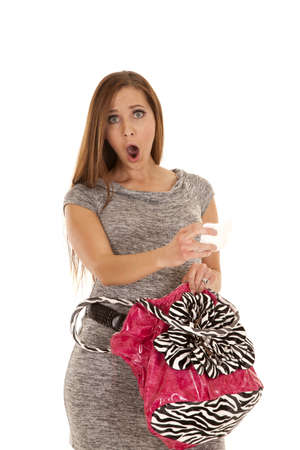 A woman with a shocked expression on her face pulling a receipt out of her purse.の写真素材