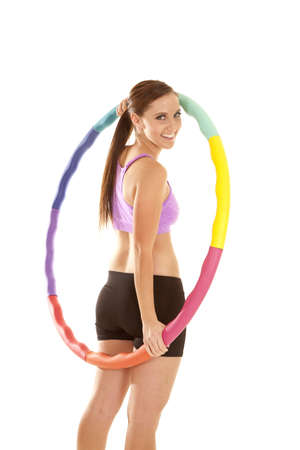 A woman holding on to her weighted hoola hoop with a smile on her lips.の写真素材