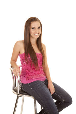 A woman sitting on her stool with a smile on her face in her pink top.の写真素材
