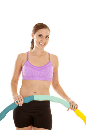 A woman with a smile on her face holding on to her weighted hoola hoop.の写真素材