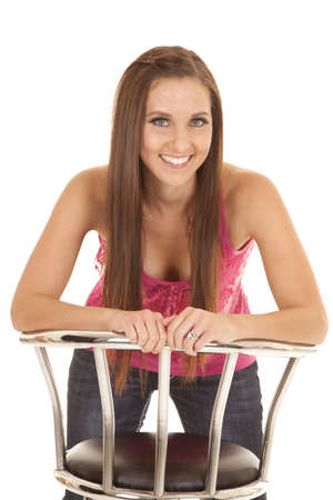 A woman leaning over her stool with a smile on her face.の写真素材