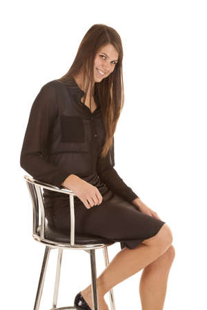 A woman with a smile on her face sitting in a stool showing off her confidence.の写真素材