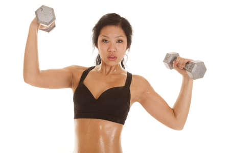 An Asian woman in her black sports bra with sweat dripping off her body lifting weights.の写真素材