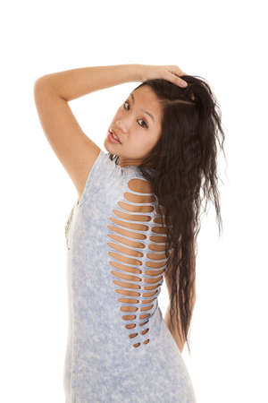 A Asian teen woman looking over her shoulder holding on to her hair with a serious expression on her face.の写真素材