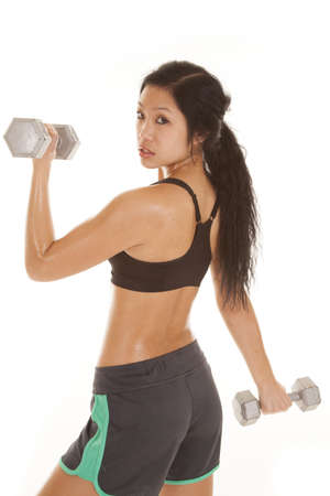 a woman looking over her shoulder while working out with weights.の写真素材