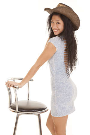 A woman in her cowgirl hat standing by her stool with a smile on her face.の写真素材
