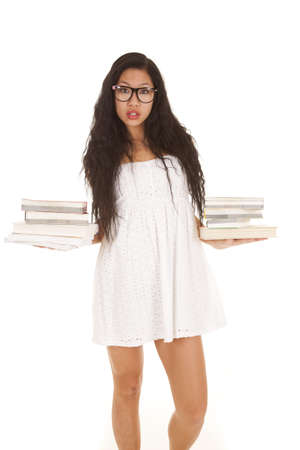 A woman in her white dress and glasses holding books in both hands.の写真素材