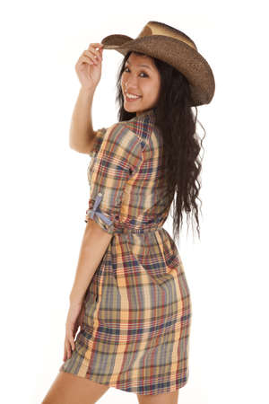 An Asian woman with a smile on her lips touching the brim of her cowgril hat.の写真素材