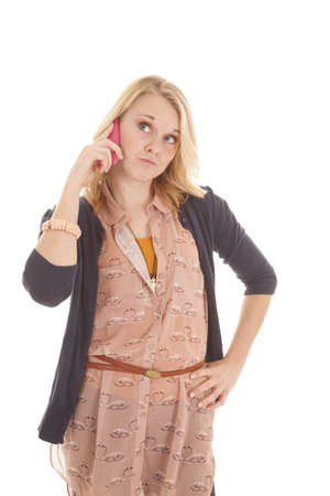 A woman holding on to her pink phone with her hand on her hip with a funny expression on her face.の写真素材