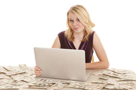 A woman sitting at a desk surrounded by American money, and she is working on her computer.の写真素材