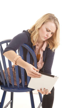 a woman sitting on her chair with a confused expression on her face, while looking at her tablet.の写真素材