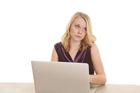 A woman sitting at her desk daydreaming while she should be working on her computer.の写真素材