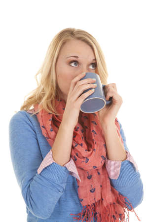 A woman enjoying a drink while she is wearing her scarf and sweater.の写真素材