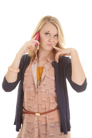 A woman with her finger up by her mouth talking on the phone.の写真素材