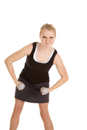 A woman with a funny expression on her face flexing and holding on to her weights.の写真素材