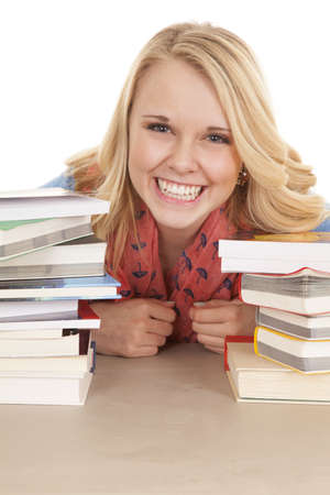 A girl with her head peeking through her stacks of books with a smile on her lips.の写真素材