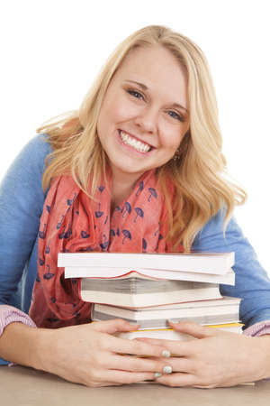 A girl holding on to her stack of books with a smile on her lips.の写真素材