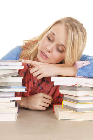 A girl resting her head on a stack of books peeking in another book.の写真素材