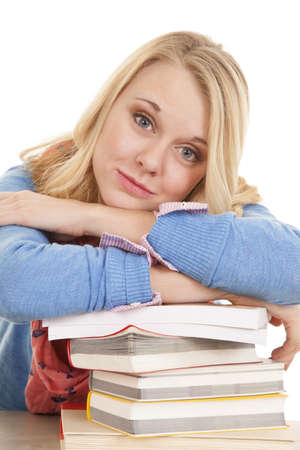 A woman with her arms on top of a stack of books with a small smile on her lips.の写真素材