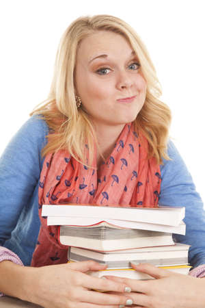 A woman with a smirk on her face with her arms around a stack of books.の写真素材