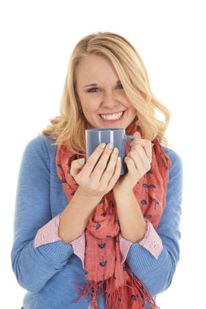 A woman with a big smile on her face holding on to her blue mug.の写真素材